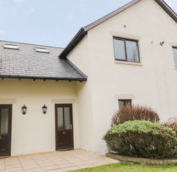 A view of two adjoining front doors with numbers 24 and 25 on a white building with windows and bushes at Whitbarrow 24 in Penruddock