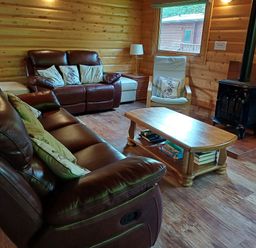 A living room with leather sofas a wooden coffee table an armchair and a wood stove at 64 Acorn Lodge Kenwick Park in Louth