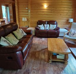 A living room with brown leather sofas a wooden coffee table wooden walls and floor at 64 Acorn Lodge Kenwick Park in Louth