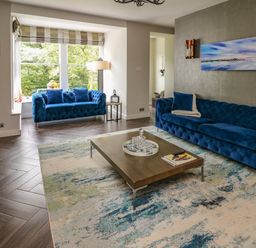 A living room with two blue sofas a wooden coffee table and large window at Glamorgan House in Cardiff
