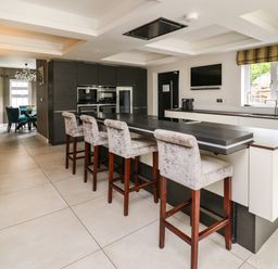 A kitchen with island seating and high chairs near a window at Glamorgan House in Cardiff