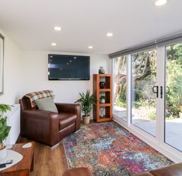 A living room with leather armchairs a colorful rug and large glass sliding doors at Riverview @ 1 Brunel View in Saltash