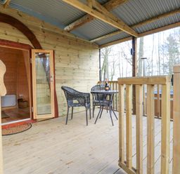 An outdoor wooden deck with a round table and two chairs bottle and glasses on the table at The Leveret in Eppleby