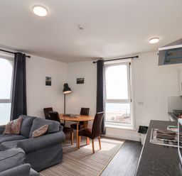 A living room with two sofas a dining table with four chairs and a kitchen area at 7 Beach View Beaconsfield House in Bridlington