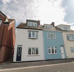 A street view of attached houses with white and blue facades and multiple windows at Quay Cottage Sea View in Poole