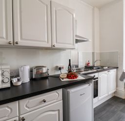 A kitchen with white cabinets microwave toaster kettle fridge and food on the counter at 4 Beach View Beaconsfield House in Bridlington