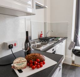 A kitchen counter with bread cherry tomatoes cheese wine glasses and a bottle of wine in 4 Beach View Beaconsfield House Bridlington