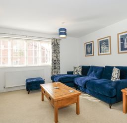 A living room with a blue sofa wooden coffee table and framed pictures on the wall at The Mill Stones in Stalham