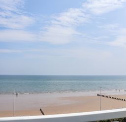 A beach with people walking near the water and wooden groynes at 4 Seaview @ Bridlington Bay in Bridlington
