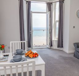 A dining area with a table set for two facing a window with a sea view at 4 Seaview @ Bridlington Bay in Bridlington