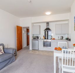 A kitchen and living area with a grey sofa and a white dining table at 4 Seaview Bridgeington Bay in Bridlington