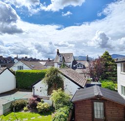 A view of residential houses with gardens and sheds under a partly cloudy sky at The Paddock in Keswick