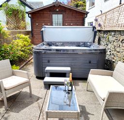An outdoor patio with a hot tub garden furniture and a wooden shed at The Paddock in Keswick