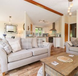 A living room with sofas and a wooden coffee table near an open kitchen at Nutkins Lodge in Beckside 5 Limefitt Park near Windermere