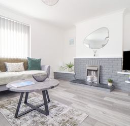 A living room with a sofa cushions coffee table and a TV near a fireplace at Apple Tree Bungalow in Lanner
