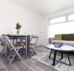 A dining area with a table set for four and a living area with a sofa and coffee table at Apple Tree Bungalow in Lanner