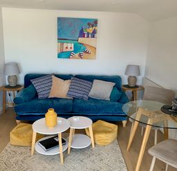 A living room with a sofa, coffee table, and dining table at Beach Cottage in Cadgwith