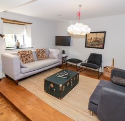 A living room with sofas a coffee table a TV and a wall picture at The Old Stables in Chipping Campden