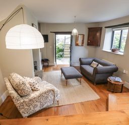 A living room with two sofas a coffee table lamp and a door leading outside at The Old Brewhouse in Chipping Campden