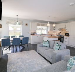 An open living room and kitchen with grey sofas and blue chairs at The Haven in Falcarragh County Donegal