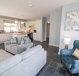 An open plan kitchen and living area with grey sofas and blue armchair at The Haven in Falcarragh County Donegal