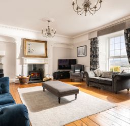 A living room with a fireplace a large window a gray sofa a blue sofa and a gray ottoman at Fron Dderw Bala