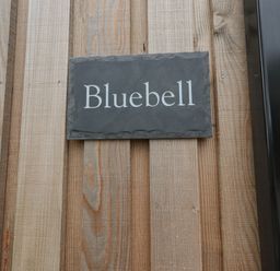 A slate nameplate with Bluebell text mounted on a wooden wall at Bluebell Cabin in Ullswater