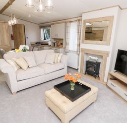 A living room with a sofa ottoman and a television next to a fireplace at 7 Wild Haven in Landford