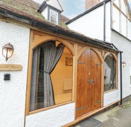 The entrance of a building with wooden double doors and arched windows with curtains at Riverside Manor in Evesham