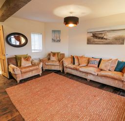 A living room with sofas and armchairs around a rug and wall art at Riverside Manor in Evesham