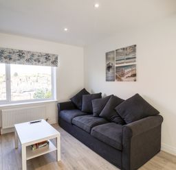 A living room with a dark sofa coffee table window and wall art at Whitby View in Whitby