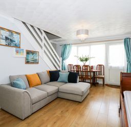 A living room with a gray sectional sofa orange and blue cushions wooden dining table with chairs and teal curtains at 63 The Waterside Holiday Park in Corton