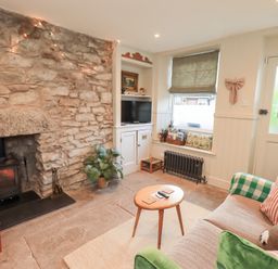 A living room with a fireplace and a sofa at Gosling Cottage Kendal