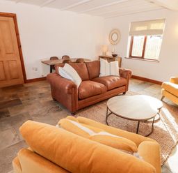 A sitting room with leather and fabric armchairs a round coffee table and a wooden dining table at Fountain Folly in Moylgrove near St Dogmaels