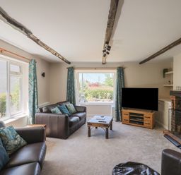 A living room with a sofa, coffee table, television, and windows at Woodstock in Chard