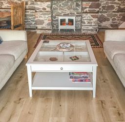 A living room with two beige sofas a white coffee table with shells on top and a small stove fireplace at Baronet's Quarters in Lynton