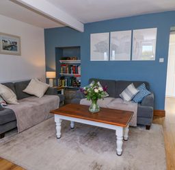 A living room with two gray sofas and a wooden coffee table with flowers on it at Towyn Hall in New Quay