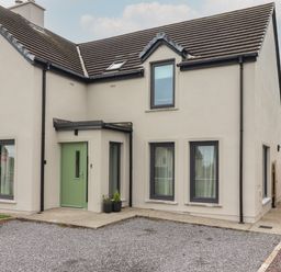 An exterior view of a two story house with a green front door and multiple windows at 19A Lighthouse Village Fenit County Kerry