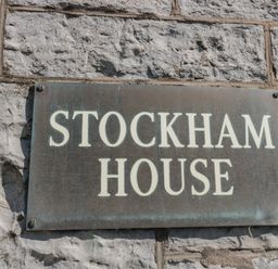 A metal sign reading stockham house mounted on a textured stone wall at 49 Esplanade in Burnham-On-Sea