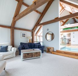 A living room with sofas and a coffee table under exposed wooden beams at Gull Rock 4 in Rock