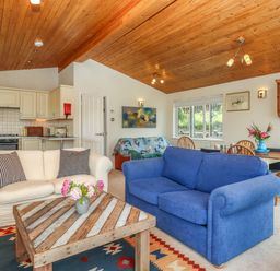 A living room with two sofas a wooden coffee table and kitchen area at Tamar View Lodge in Millbrook