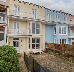 A row of three story houses with balconies and a patio area in front at 42 Crag Path in Aldeburgh