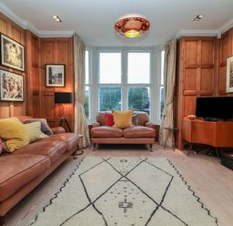 A living room with two brown leather sofas and a large window at 42 Crag Path in Aldeburgh
