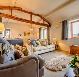 A living room with sofas a lamp a sheepskin rug a wooden trunk and flowers at Shepherds Cottage in Hawkshead