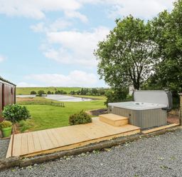 An outdoor area with a hot tub and decking at Mallard Lodge in Moscow near Galston