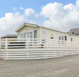 A single story mobile home with white railings and a gravel driveway at Gwel Eryri in Penmynydd near Llanfairpwllgwyngyll