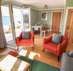A sitting area with two orange armchairs and a gray sofa near glass doors leading outside at The Annexe Meadow Croft in Haverfordwest