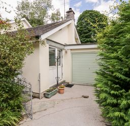 A house exterior with a green garage door plants and a small metal gate at The Lodge in Ambleside