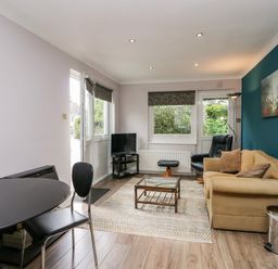 A living room with a beige sofa black armchair coffee table and television at The Lodge in Ambleside