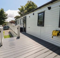 A deck with railing attached to a mobile home with windows and a hose reel at Pams Place in Crantock